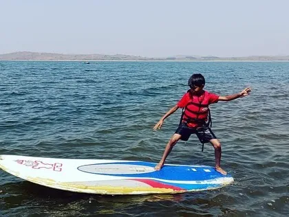A young adventurer strikes a pose on his paddleboard during a summer camp session.