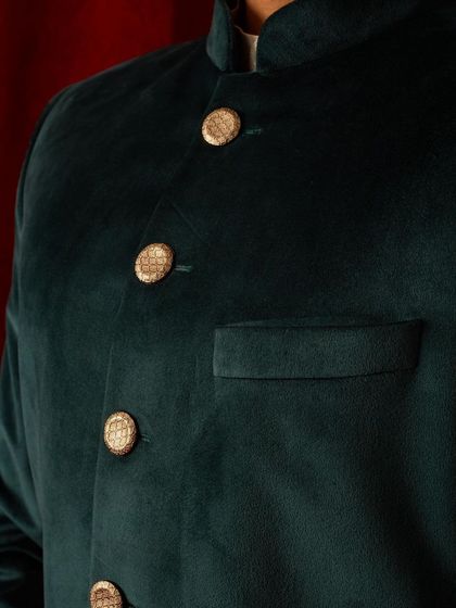 A close-up on the custom buttons and pocket of our green velvet bandhgala. Even the simplest details are thoughtfully considered to enhance the overall elegance of the garment.