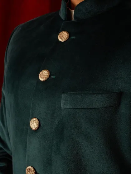 A close-up on the custom buttons and pocket of our green velvet bandhgala. Even the simplest details are thoughtfully considered to enhance the overall elegance of the garment.
