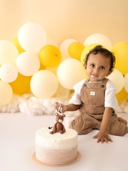 A lovely portrait of the birthday boy before the cake smash, sitting patiently with his teddy bear cake.