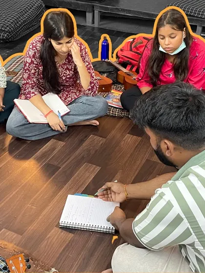 An instructor reviews a student's notes during a ukulele class. We focus on building a strong foundation, ensuring students understand the theory behind the music they play.