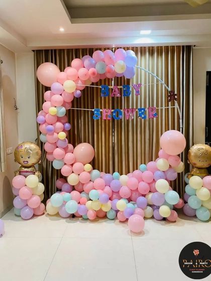 A beautiful moon-shaped balloon arch for a baby shower. The pastel colors and baby-shaped foil balloons create a soft and dreamy atmosphere.