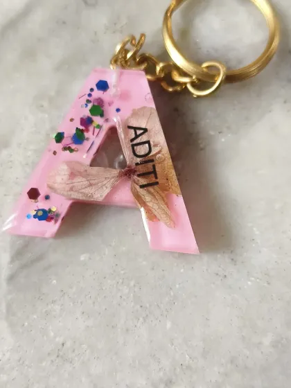 A personalized resin keychain with the initial 'A' for Aditi, featuring embedded dried flowers and glitter. A small but beautiful example of what you can create.