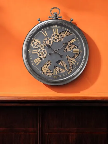 The same designer wall clock in a distressed silver finish, creating a beautiful contrast against a vibrant orange wall. This shows how versatile this timeless piece can be.