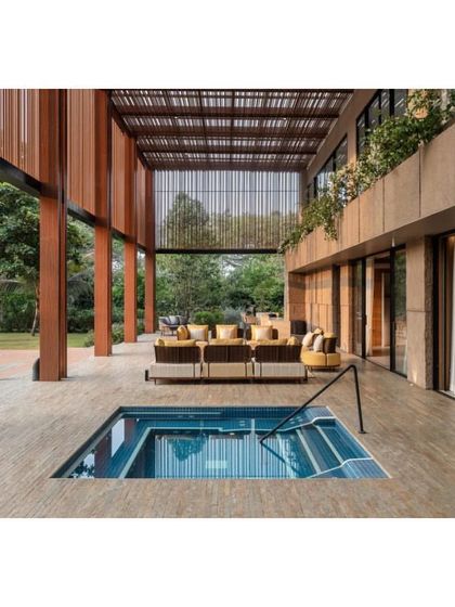 A view of the patio and plunge pool at the K House. The architecture uses natural materials and large openings to create a light, airy atmosphere that is deeply connected to its lush surroundings.