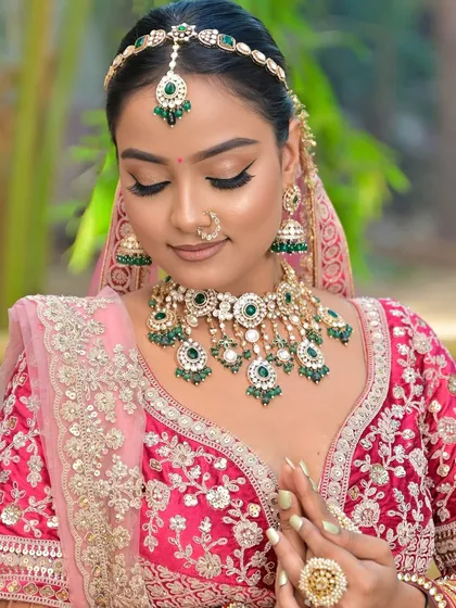 A serene portrait focusing on the intricate details of the Kundan necklace with green stone drops. The matching sheeshpatti completes this elegant bridal look.