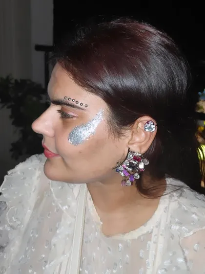 A finished look combining a bold silver glitter swipe with a delicate line of black gems above the eyebrow.