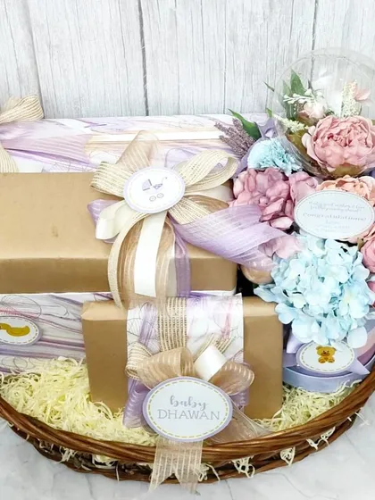 Another view of the bespoke baby shower basket, showcasing the custom 'Baby Dhawan' tags and the delicate color palette.