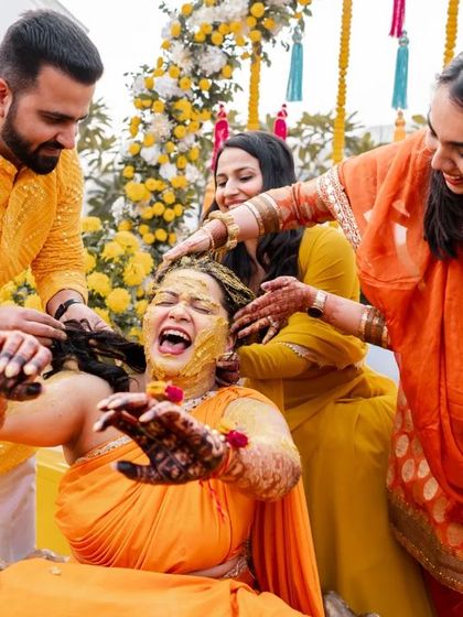 The bride's friends and family lovingly applying Haldi. This image is all about the shared joy and community of a wedding.