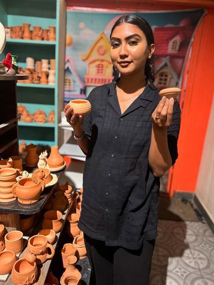 Holding up two small, unpainted terracotta pots, a guest is ready to start her next creative project.