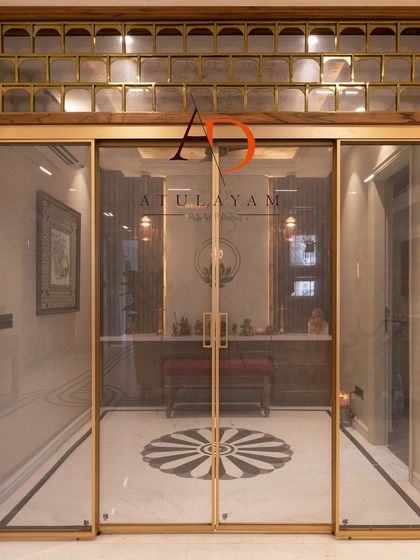 A grand entrance to a pooja room, featuring sliding glass doors with a fine mesh, a decorative transom with glass blocks, and a beautiful marble inlay floor.