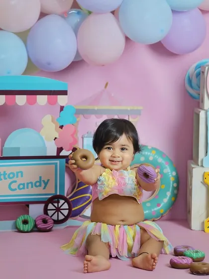 This little girl is having a great time with the donut props in her candyland first birthday session. It's all about interactive and playful setups.