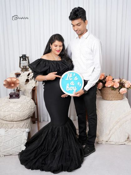 A studio gender reveal with the couple holding a sign that says "It's a boy!".