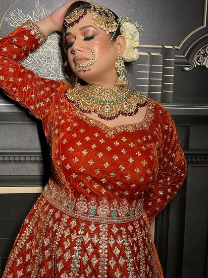 Here is a close-up of a royal bridal outfit I designed. You can see the rich texture of the red-orange velvet and the detailed silver and turquoise embroidery around the neckline. I focus on using luxurious fabrics to create these timeless pieces.