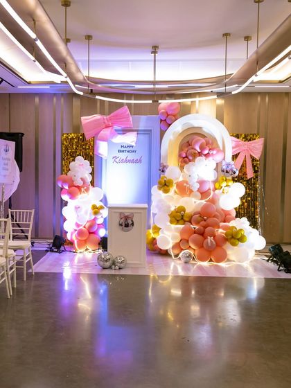 The full view of the sophisticated pink and gold party setup, featuring large bows, a sequin backdrop, and a beautiful balloon arch.