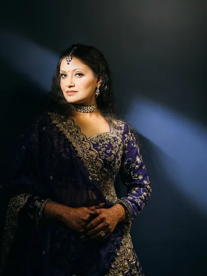 A dramatic and glamorous sangeet look, with artistic lighting highlighting the deep blue outfit.