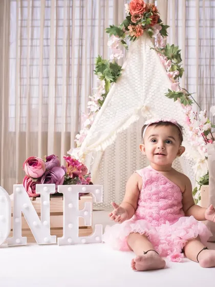 A princess in pink. This little girl is all smiles in her beautiful floral teepee setup for her first birthday.