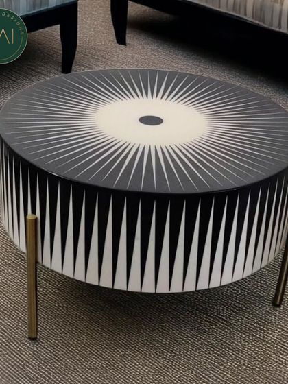 This striking coffee table features a black and white sunburst pattern, creating a bold graphic statement. Supported by slender brass legs, it's a centerpiece that combines artistic flair with modern design.