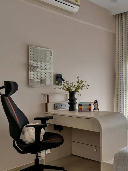 A sleek and modern study corner perfect for a teen's room. The light wood desk with curved edges is paired with a comfortable gaming chair and a pegboard for organization.