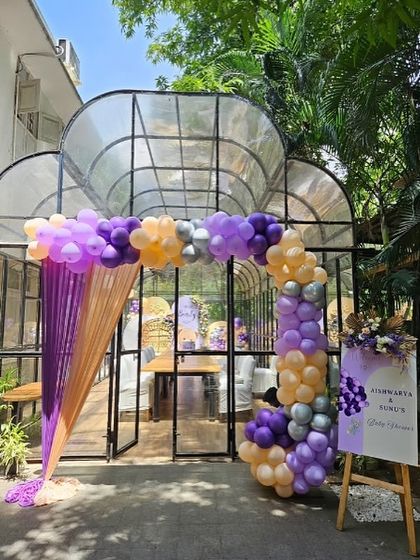The entrance to the glasshouse venue, decorated with a beautiful balloon arch in purple, peach, and silver.