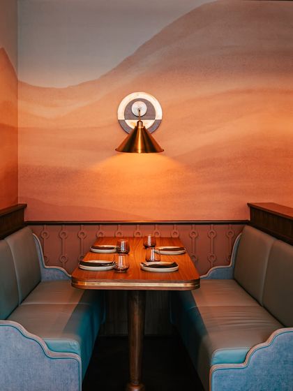 A four-person booth set against our signature desert-hued mural. This intimate seating arrangement is perfect for small family dinners, client meetings, or a quiet meal away from the main buzz.