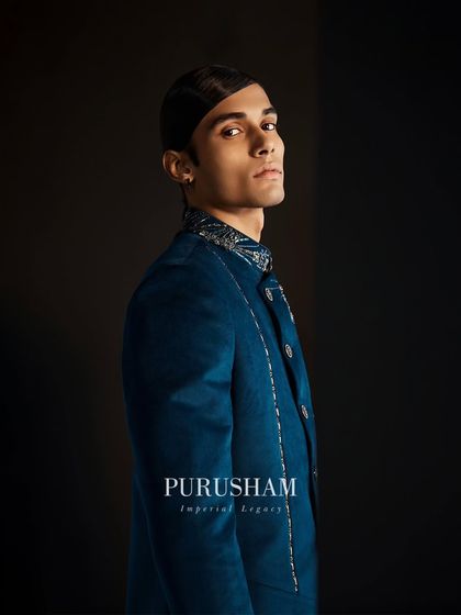 A profile view of the deep teal jacket. The intricate collar and shoulder embroidery add a touch of modern royalty to this striking piece.