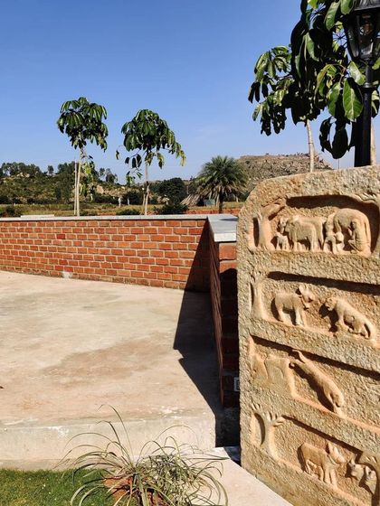 A detailed shot of a carved stone slab, or 'Shasana', placed near the informal amphitheater at the Nandi Hills project. This artistic element adds a layer of local culture and storytelling to the landscape design.
