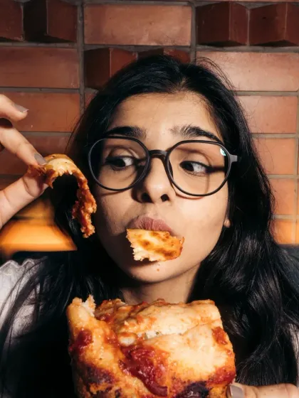 A customer playfully enjoying the crust of her pizza. It's about having fun with your food.