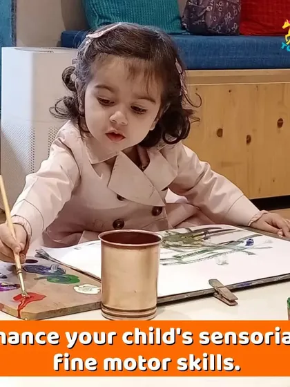 A toddler carefully dabs her paintbrush, a perfect example of our parent-toddler sessions. These activities are designed to enhance fine motor skills and sensory development.