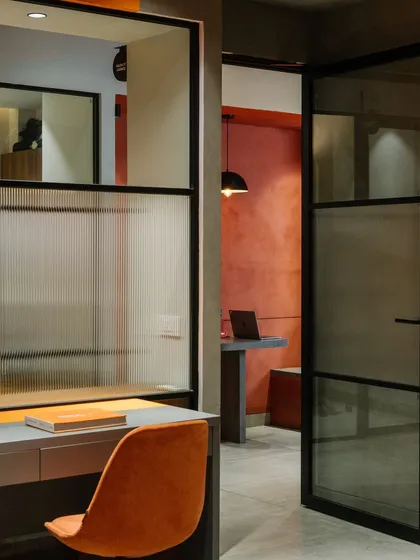 A view from a workspace into the corridor, showing the use of fluted and clear glass to balance privacy and openness.