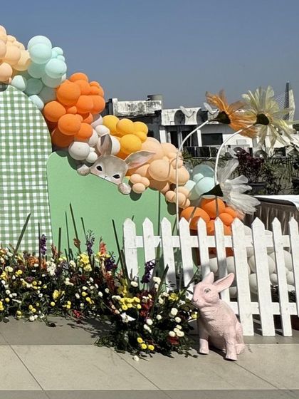 Another angle of the bunny garden decor, highlighting the pink bunny prop and the way the balloon garland playfully peeks over the picket fence.