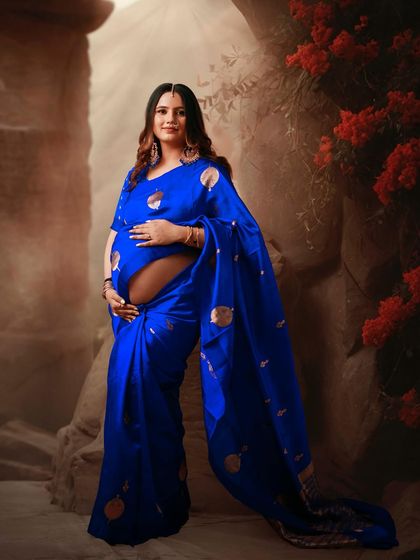 A beautiful portrait of a mom-to-be in a vibrant blue saree. The creative backdrop adds a touch of magic to this traditional look.