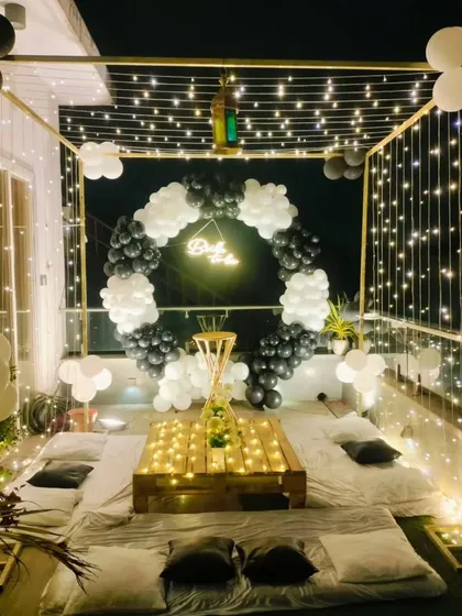 We can transform any space, including a terrace, into a magical setting. This "Oh Baby" celebration features a cozy cabana-style setup with fairy lights, a black and white balloon ring, and comfortable floor seating for an intimate and stylish event under the stars.