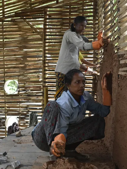 Two women masons applying the wattle and daub technique. Through training and guidance, these women become confident, skilled builders, transforming their own lives and their communities.