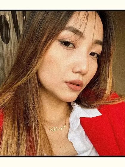 A customer photo showing our gold script name necklace. It's a great example of how this personalized piece looks as part of a stylish, everyday outfit.