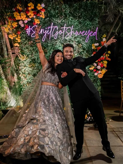 Pure celebration! This fun shot captures the energy of the Sangeet night, with the couple looking ecstatic and the bride's silver lehenga shining under the lights.