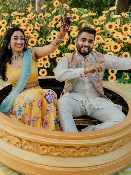 The couple enjoying their unique Haldi setup, surrounded by a sea of bright yellow sunflowers.