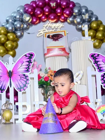 I focus on capturing the little moments, like this one from a first birthday party. The butterfly-themed decor and candid shot of the birthday girl with her party hat show how I combine photography with a great setup to create lasting memories.
