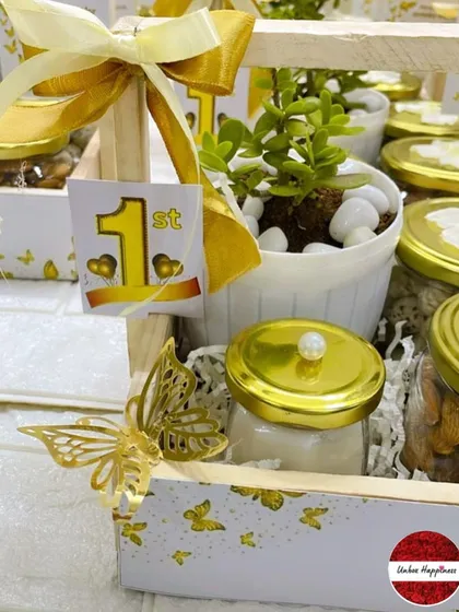 This image details the golden butterfly embellishment and the "1st" birthday tag on the elegant return gift basket.