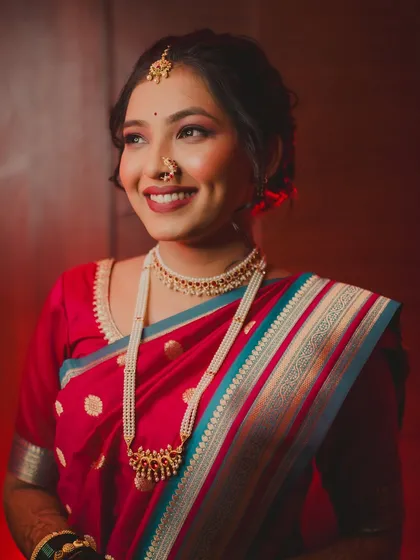 The bride looks away with a dreamy, happy smile. This portrait, with its warm red background, highlights her elegant profile and the joy of her engagement day.