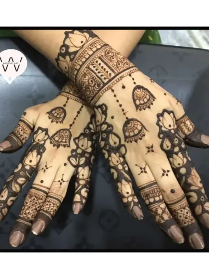 A back-hand design for a wedding guest with hanging jhumkas and lotus flowers.