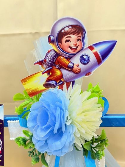 A close-up of the topper for the space-themed hamper, showing a happy little astronaut riding a rocket.