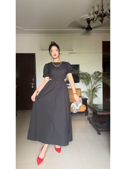 Another angle of this chic black dress. The puff sleeves add a touch of romance to the otherwise modern design.