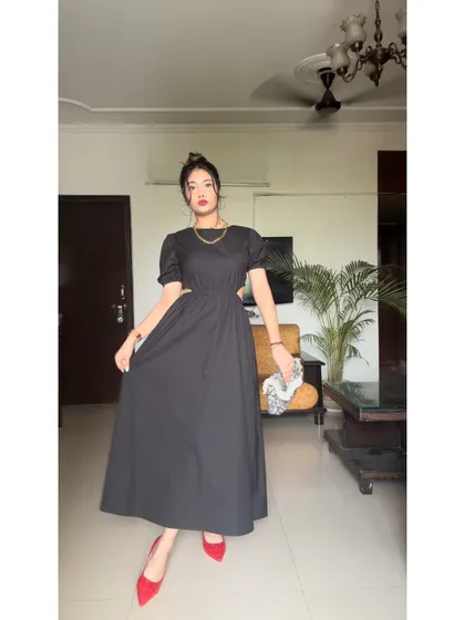 Another angle of this chic black dress. The puff sleeves add a touch of romance to the otherwise modern design.