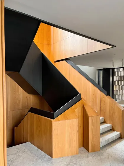 A staircase is more than a utility; it is a central sculpture. This design features a dynamic interplay of geometric oak panels and black metal, creating a powerful visual journey between floors that is both functional and artistic.