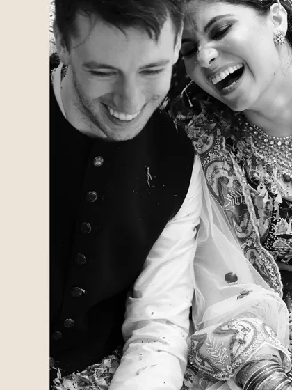 A beautiful black and white candid of Nicholas and Kriti sharing a genuine laugh together, capturing their easy chemistry and happiness.