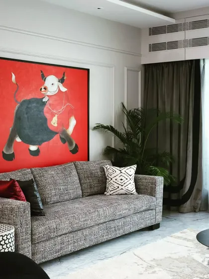 A shot of the living area showcasing the large red bull painting as the focal point. The neutral-toned sofa and simple decor allow the artwork to command attention.