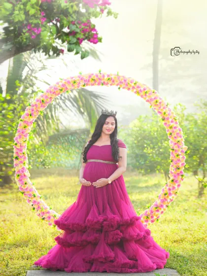 A beautiful solo portrait in a wine-colored ruffled gown, framed by a circular floral prop.