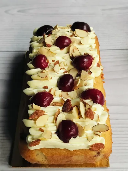 This is my Cherry Almond Tea Cake. It’s a moist almond cake with sweet cherry flavors, topped with almond buttercream, fresh cherries, and crunchy sliced almonds.