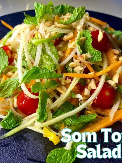 A fresh and zesty Som Tom Salad. This Thai-inspired salad is made with shredded green papaya, carrots, cherry tomatoes, and peanuts, all tossed in a tangy dressing.